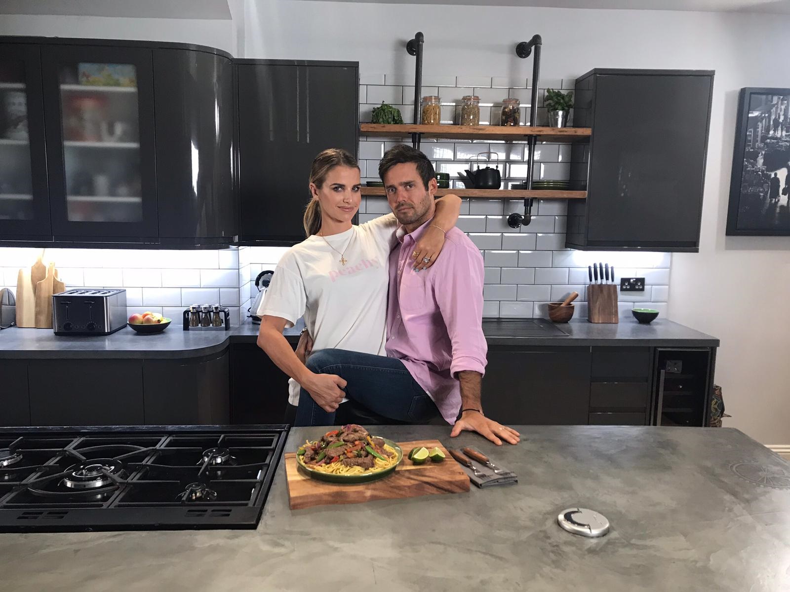 Spencer Matthews, Vogue Williams sitting on a kitchen counter with pizza